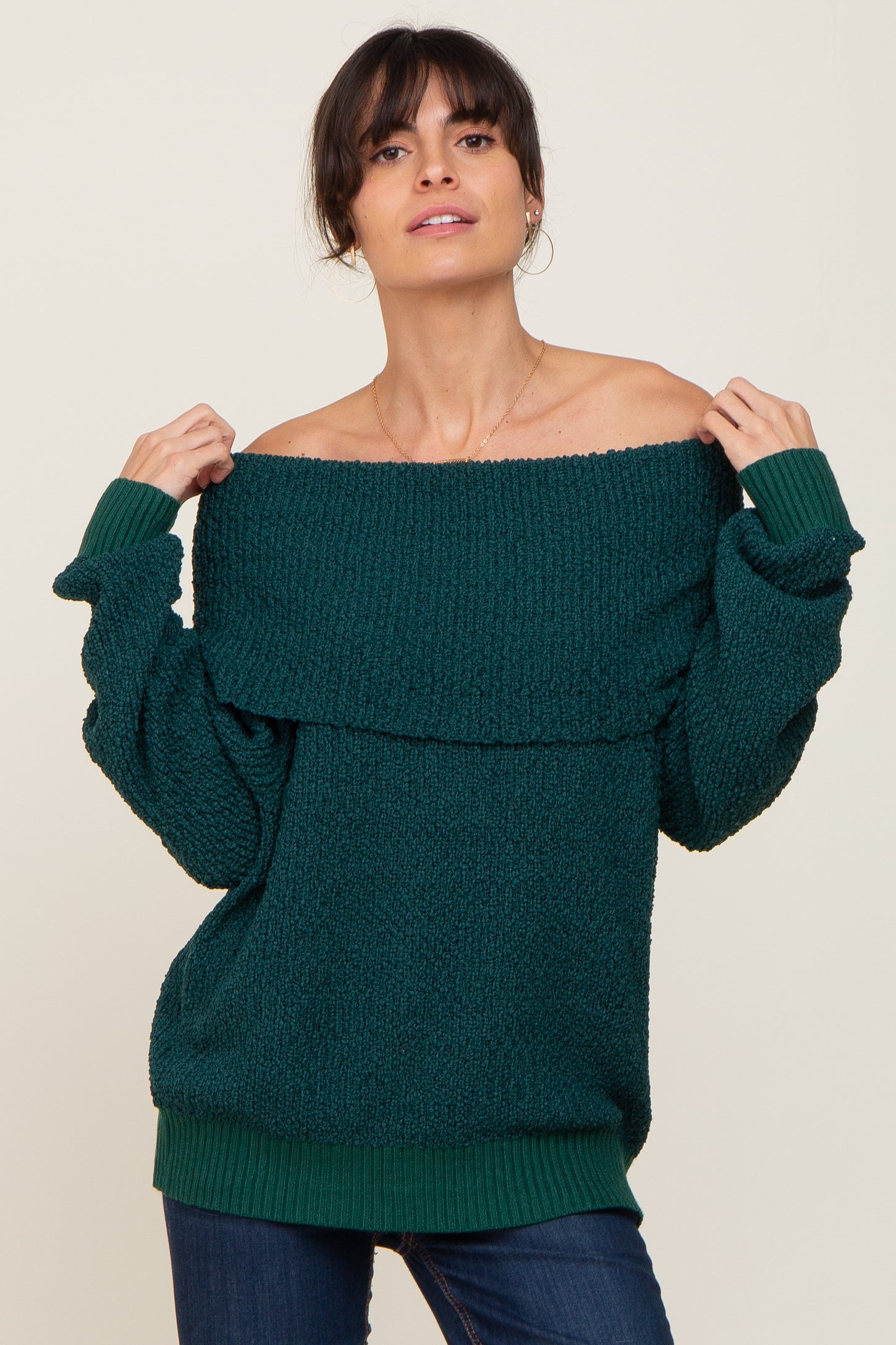 woman wearing a dark green off-the-shoulder sweater with a textured design and relaxed fit