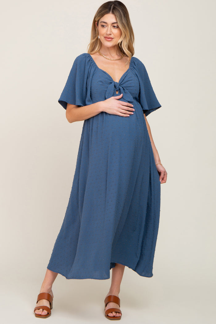 woman wearing a navy blue maternity dress with a knot detail and short sleeves, showing her baby bump