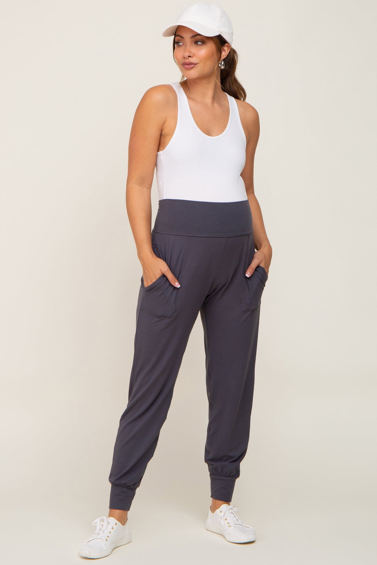 woman wearing a white tank top and gray maternity joggers with pockets and a high waistband