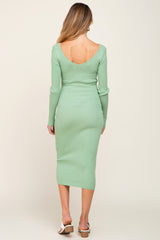 woman wearing a mint green long sleeve ribbed maternity dress with a deep back neckline