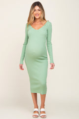 woman wearing a light green long sleeve maternity dress that hugs her baby bump