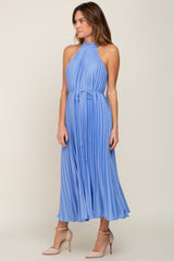 woman wearing a light blue pleated halter neck midi dress styled with a tie waist detail and beige heels