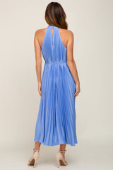 woman wearing a light blue pleated halter neck midi dress, showing the back view and a flowing silhouette