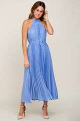 woman wearing a pleated halter neck midi dress in light blue with a tie waist