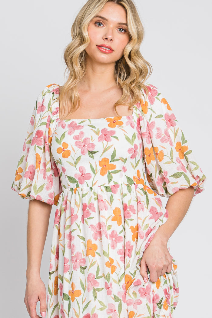 woman wearing a white floral puff sleeve midi dress with pink and orange flowers