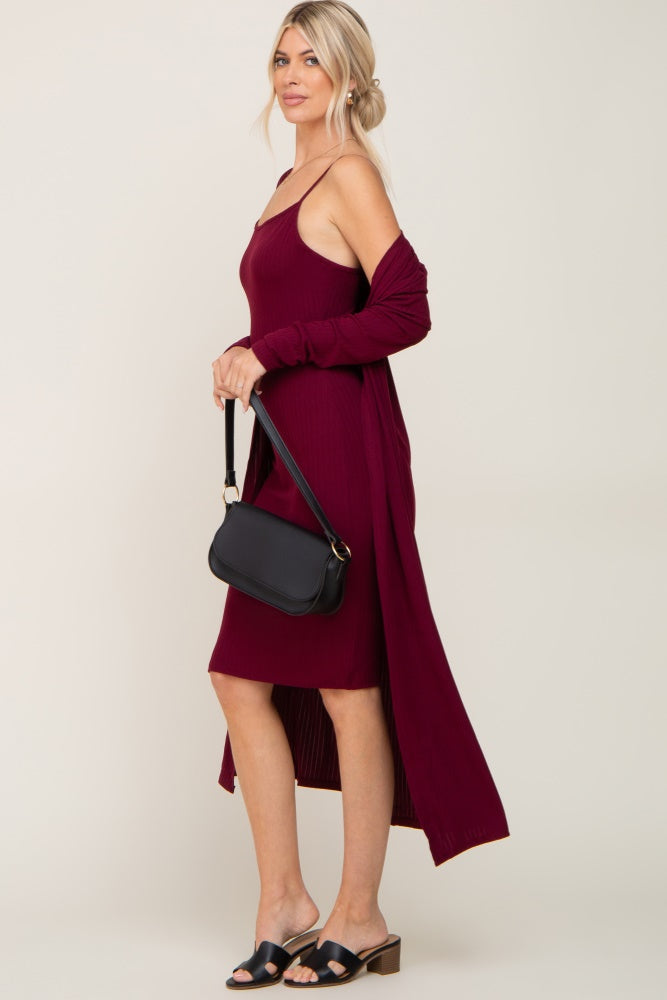 woman wearing a burgundy midi ribbed dress with thin straps and a long cardigan, accessorized with a black handbag and slides