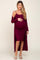 woman wearing a burgundy ribbed maternity dress with a matching long cardigan and holding her baby bump