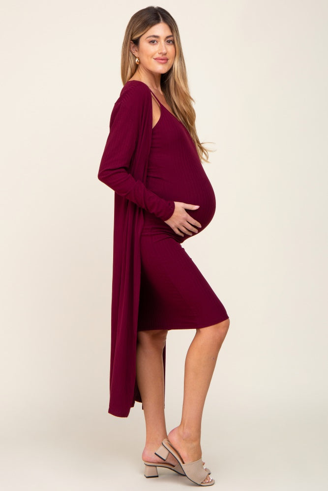 woman wearing a burgundy maternity dress with a long cardigan, showcasing her baby bump