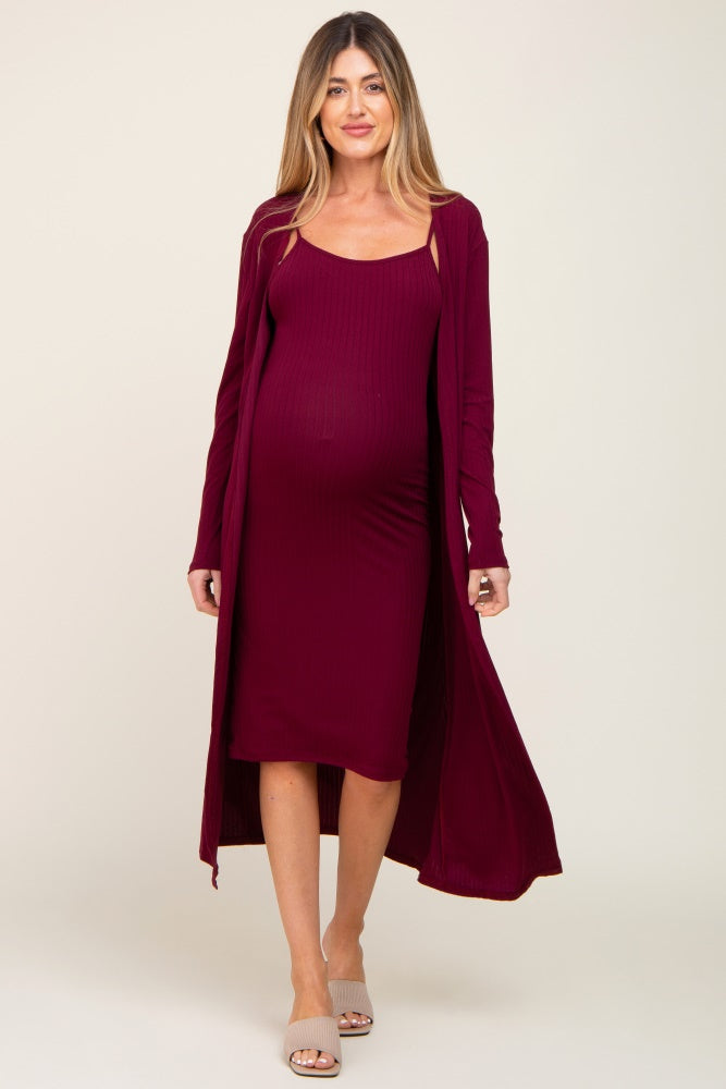 woman wearing a burgundy maternity dress with a matching long cardigan, highlighting her baby bump.