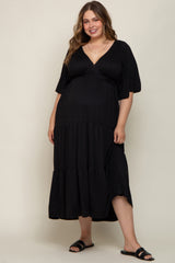 woman wearing a black maternity plus maxi dress with a v-neck and tiered design, showing off her baby bump