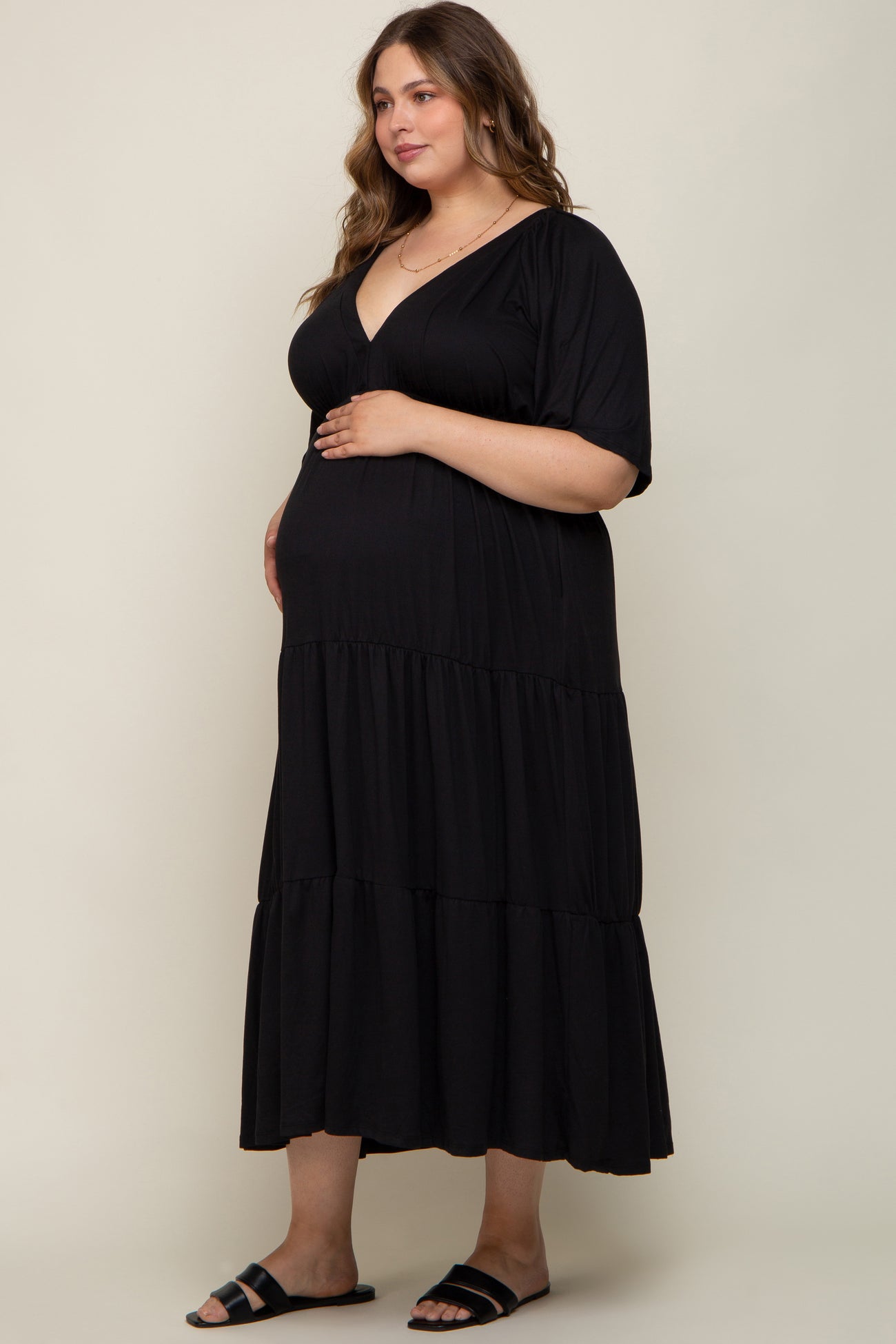woman wearing a black maternity plus tiered maxi dress with short sleeves and a visible baby bump