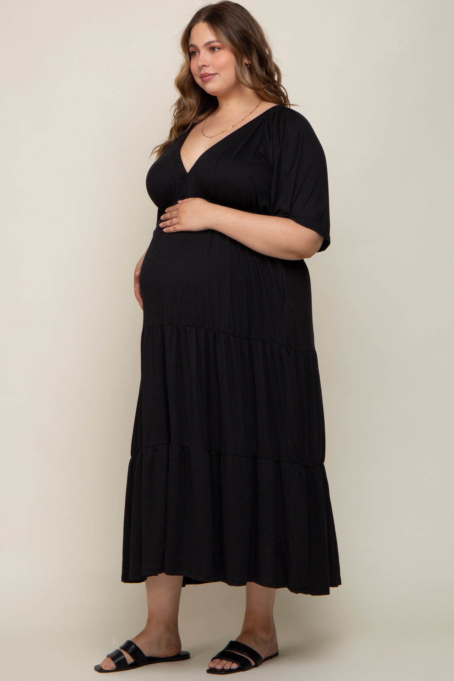 woman wearing a black maternity plus tiered maxi dress with short sleeves and a visible baby bump