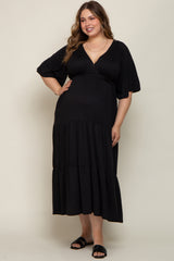woman wearing a black maternity plus maxi dress with a v-neckline and flutter sleeves, styled with flat sandals