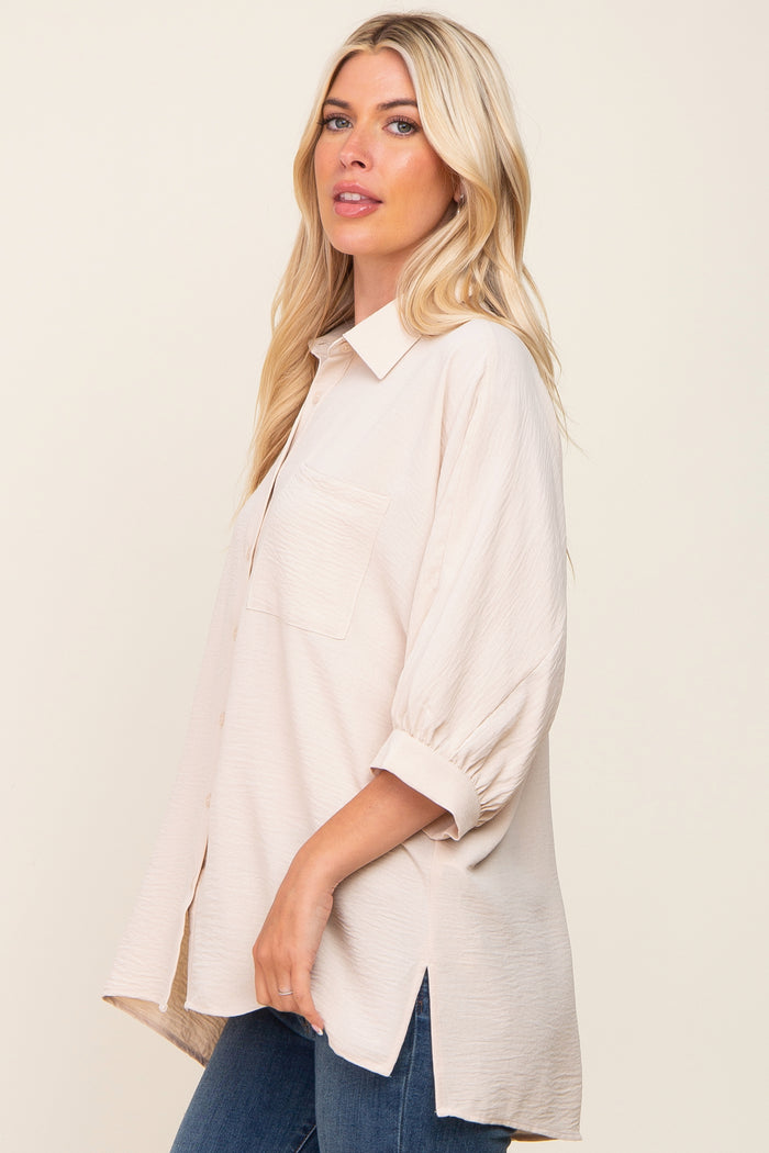 blonde woman wearing a cream oversized button-down shirt with three-quarter sleeves and blue jeans