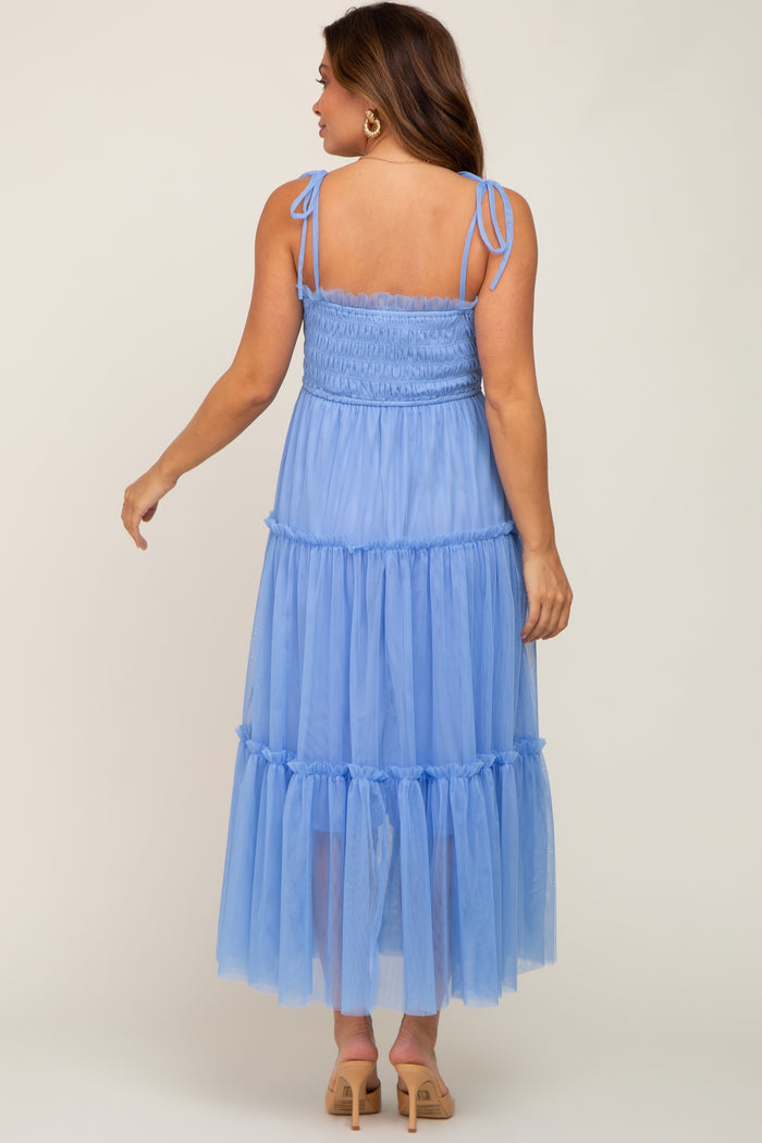 woman wearing a light blue maternity maxi dress with smocked bodice and tiered tulle skirt, seen from the back