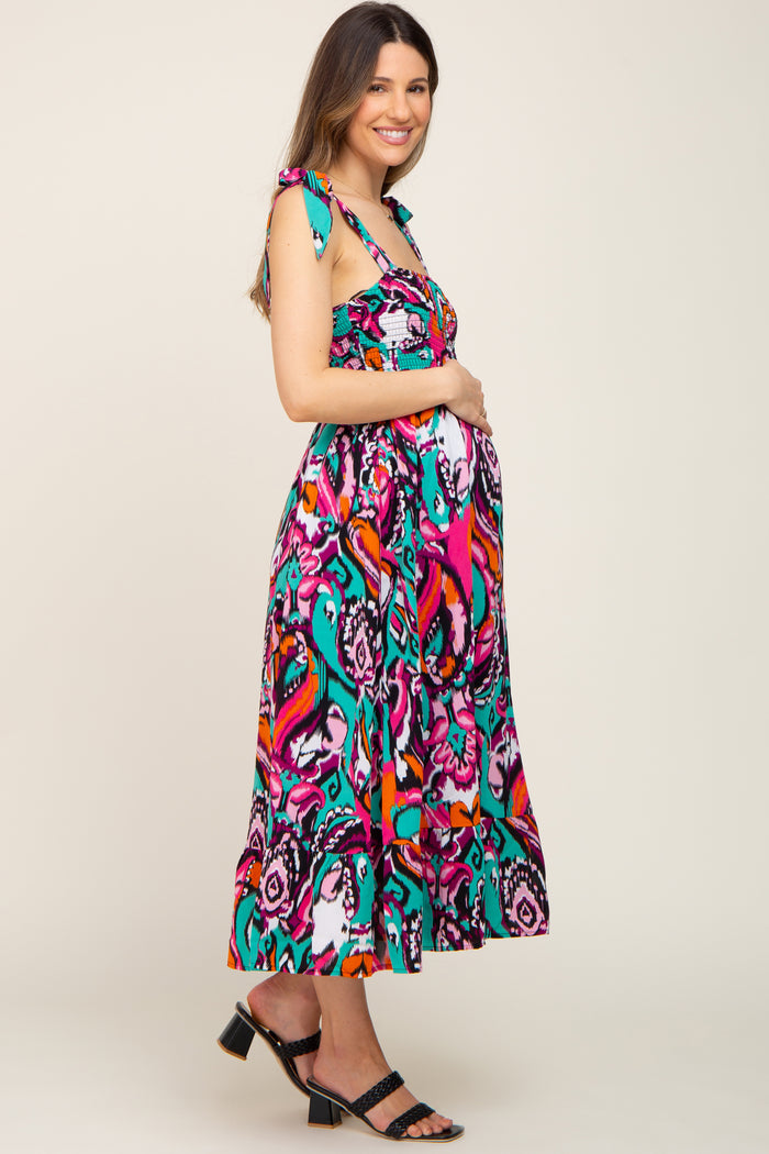 woman wearing a vibrant multicolored maternity maxi dress with tie shoulder straps and visible baby bump