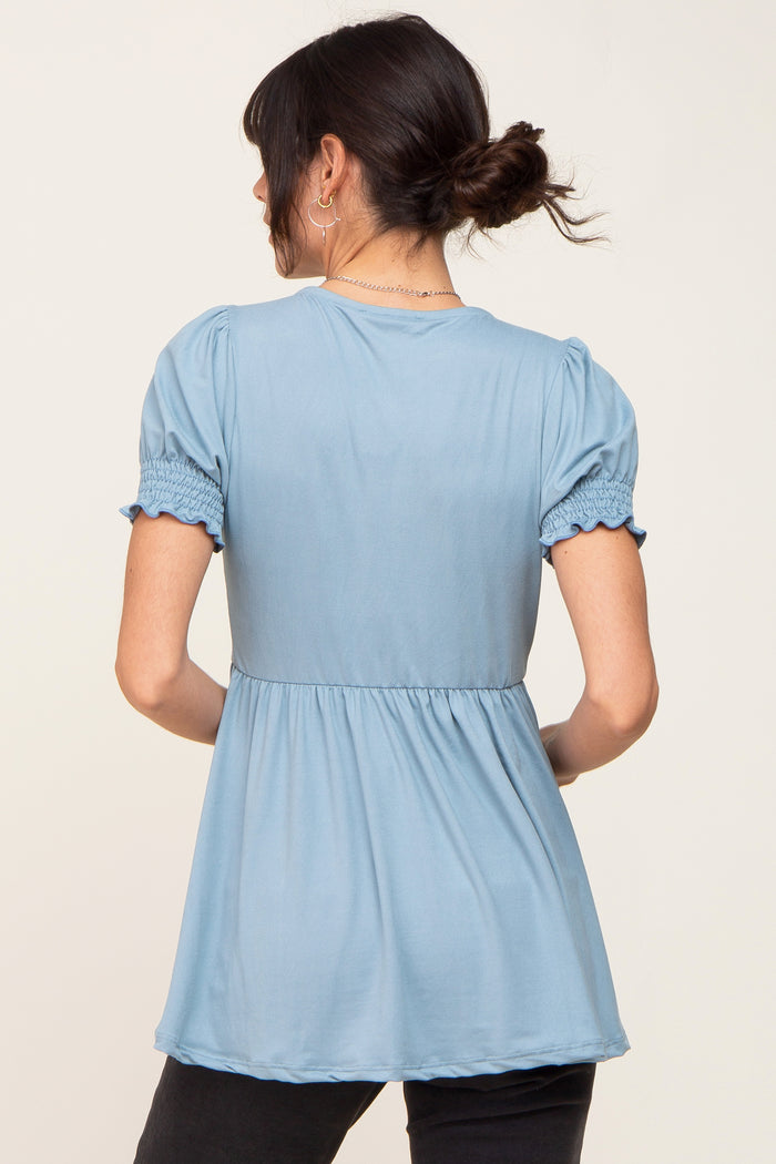 woman wearing a light blue puff sleeve top with a gathered waist and back view