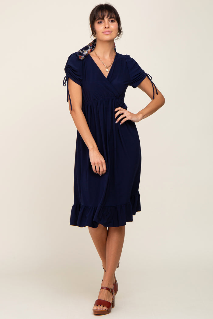 woman wearing a navy blue short sleeve wrap dress with tie details and a ruffled hem