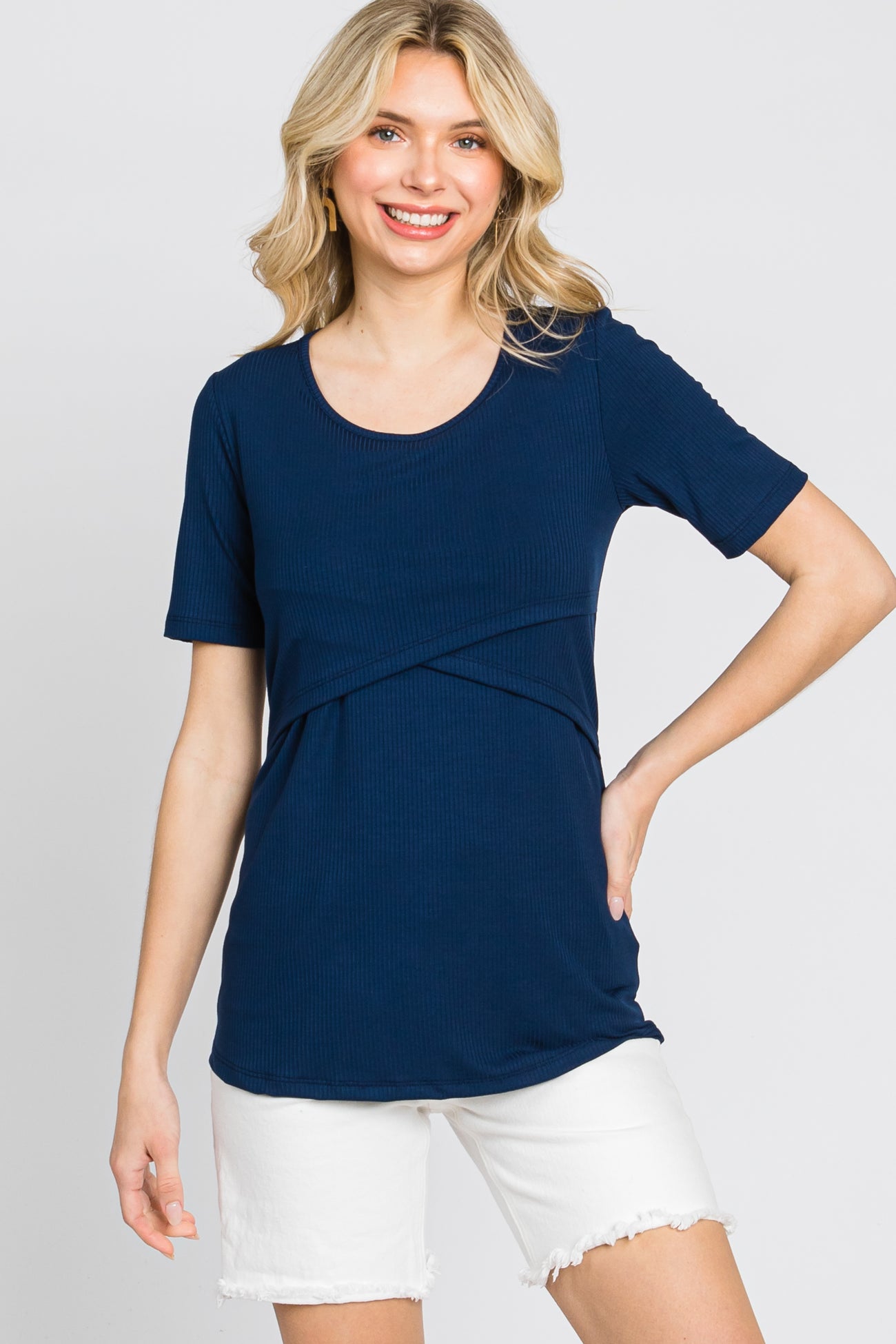 woman wearing a navy blue short sleeve top with a twist detail and paired with white shorts