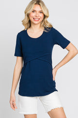 woman wearing a navy blue short sleeve top with a twist detail and paired with white shorts