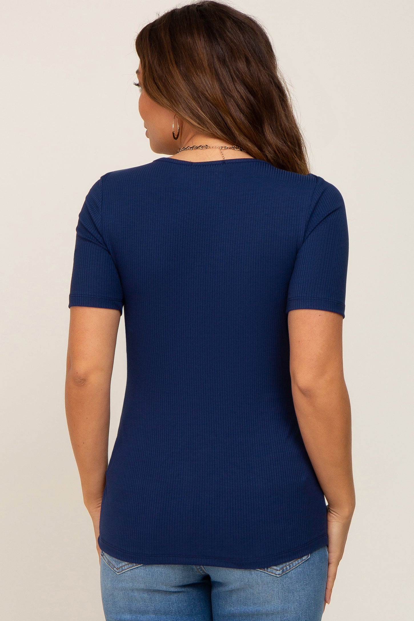 woman wearing a navy blue short sleeve maternity top, shown from the back, paired with light blue jeans