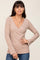 woman wearing a beige long sleeve wrap top with a deep v-neck and bell sleeves
