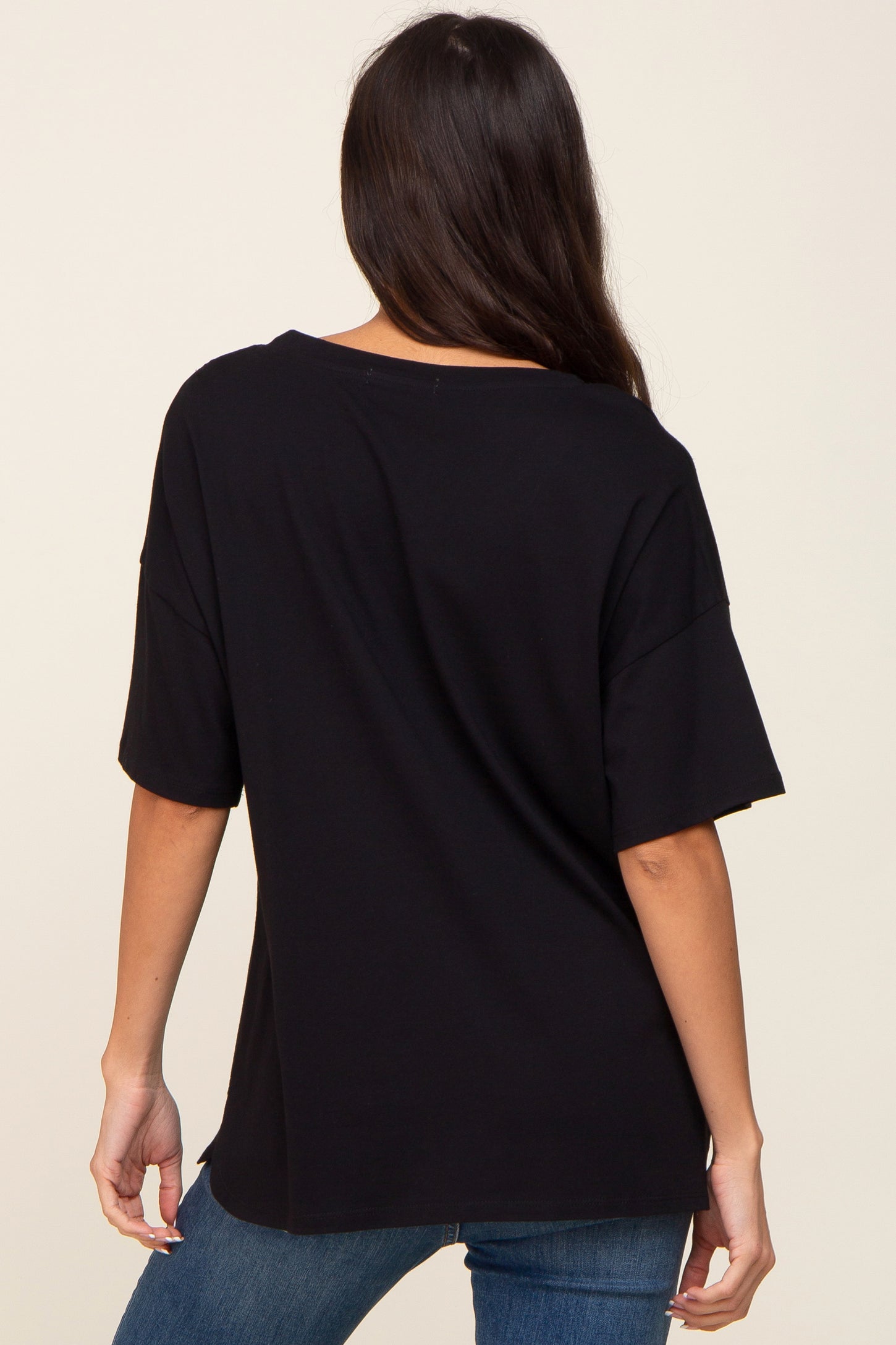 woman wearing a black oversized t-shirt, showing the back view styled with blue jeans