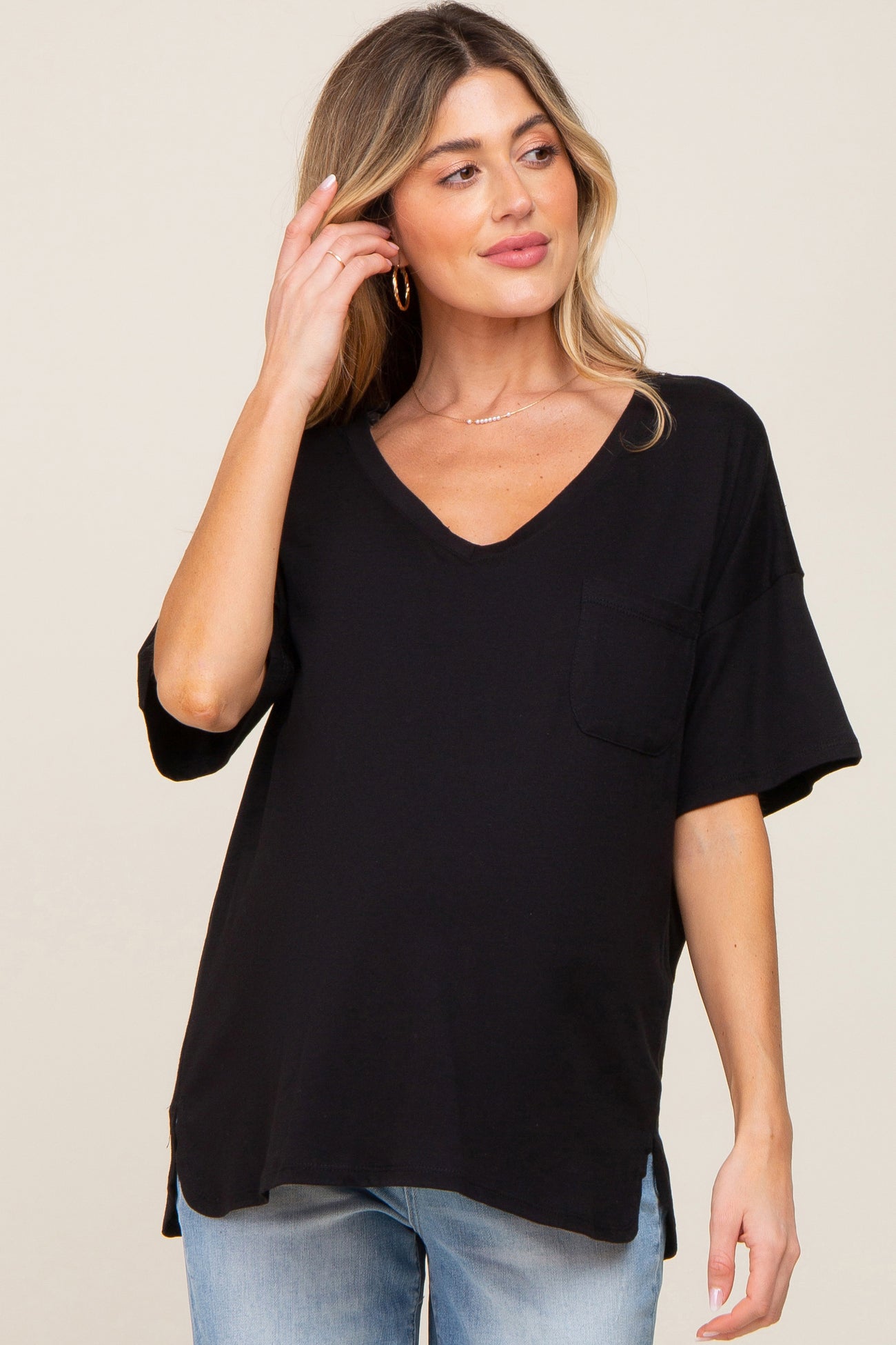 woman wearing a black maternity top with a v-neck and short sleeves, featuring a pocket and side slits