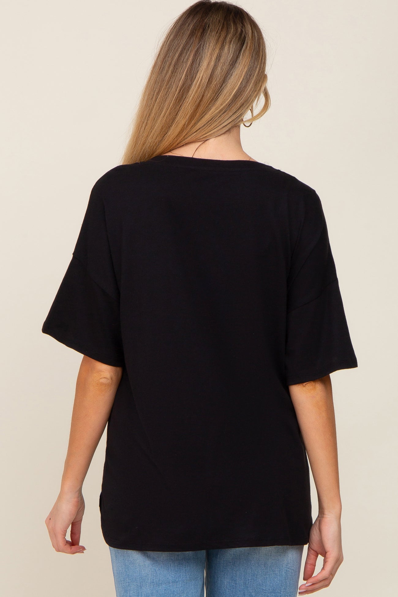 Back view of a woman wearing a black oversized short sleeve t-shirt and blue jeans