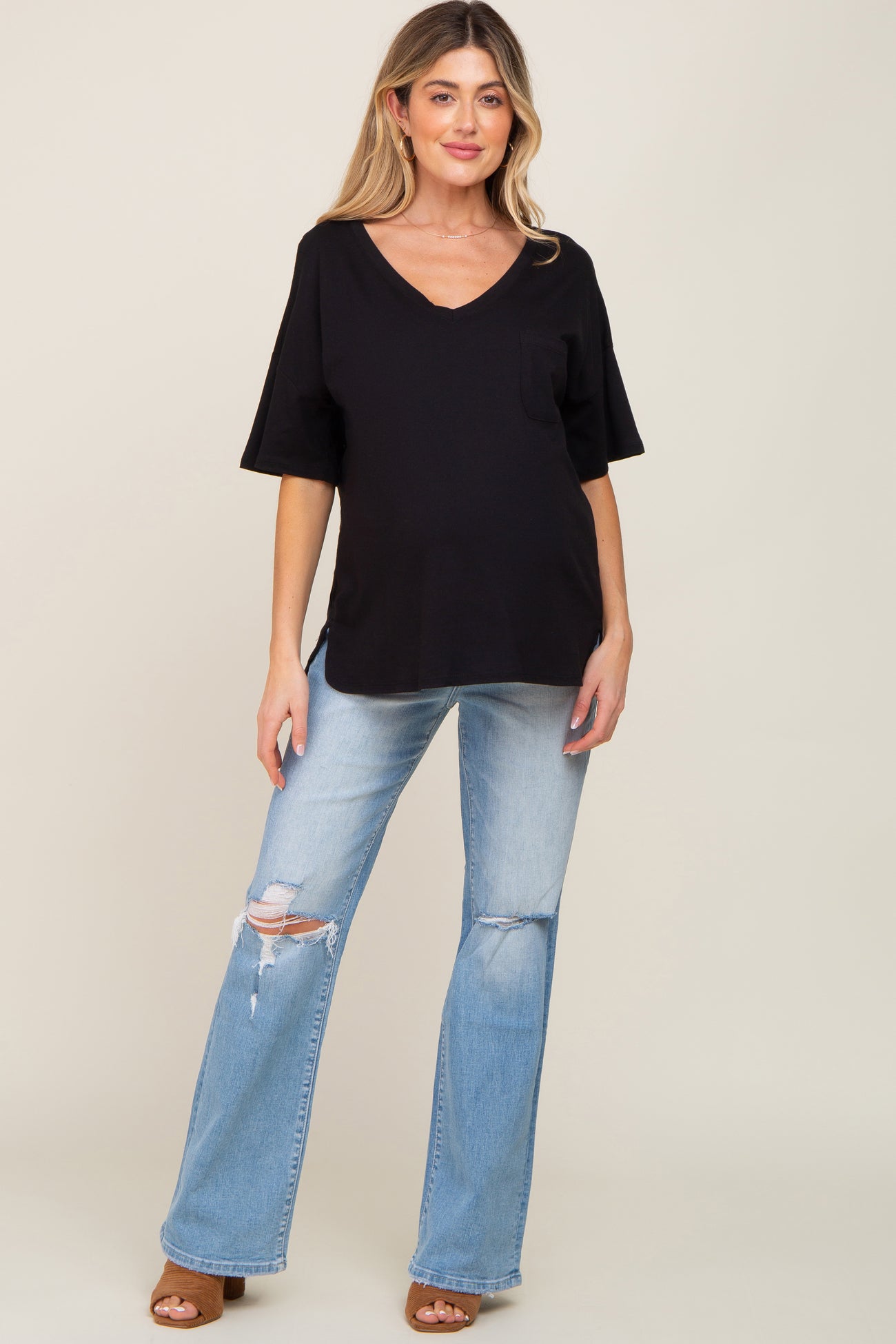 woman wearing a black v-neck maternity top with a pocket and light blue distressed flared jeans