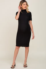 woman wearing a black ribbed short sleeve maternity dress with a scalloped hem and a visible baby bump