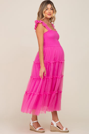 woman wearing a bright pink tiered tulle maternity dress with ruffle straps and a visible baby bump