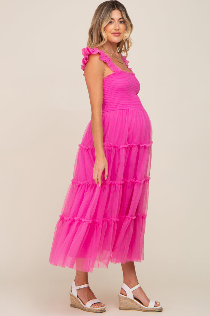 woman wearing a bright pink tiered tulle maternity dress with ruffle straps and a visible baby bump