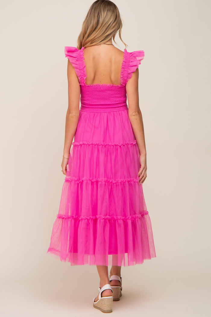 woman wearing a pink tiered maternity dress with ruffled straps, showing a smocked back and ankle length skirt