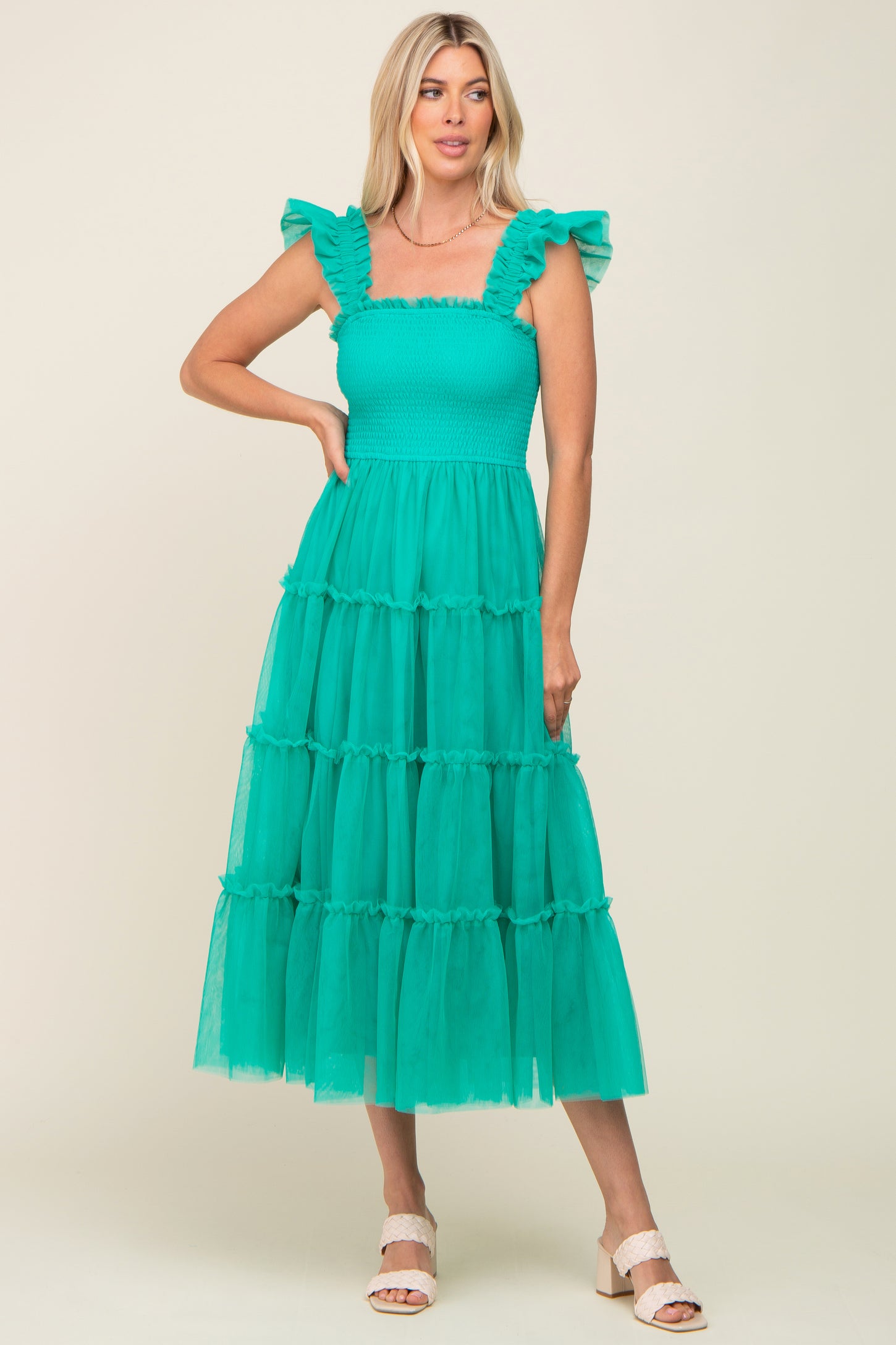 woman wearing a teal tiered midi dress with ruffle sleeves and smocked bodice