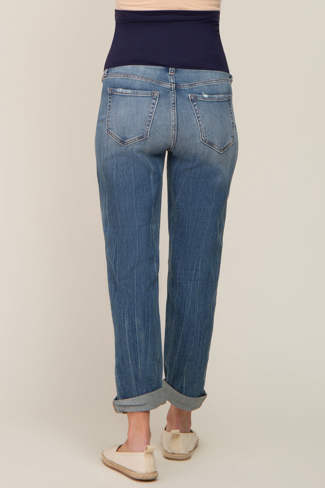 woman wearing a pair of light blue maternity jeans with a dark blue over-the-bump waistband, viewed from the back