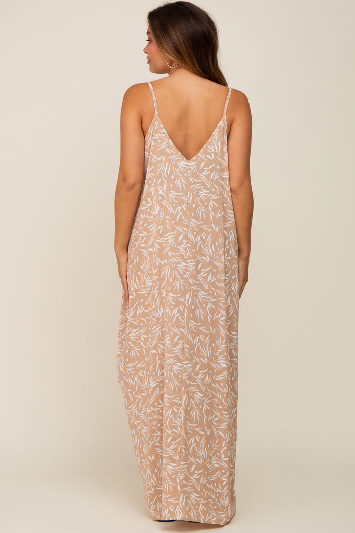 woman wearing a beige maternity maxi dress with white leaf print and thin straps, showing the back view