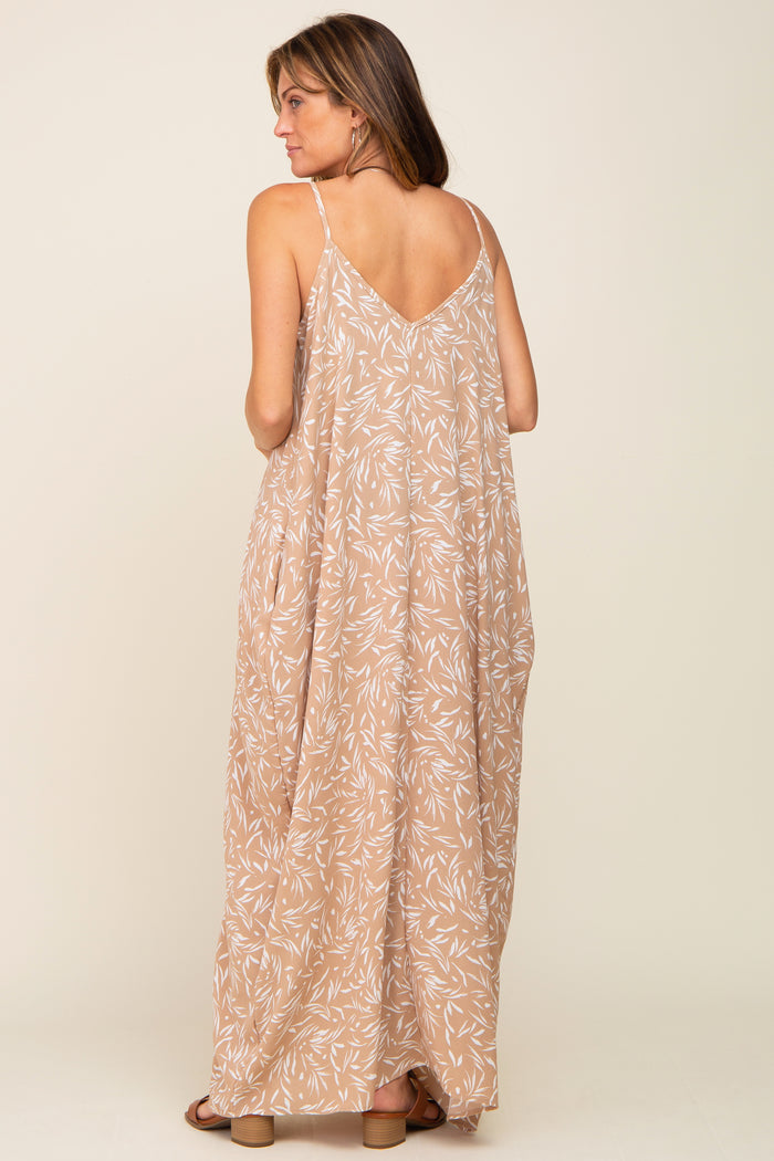 woman wearing a beige maxi dress with a leaf print and a v-back detail, shown from the back