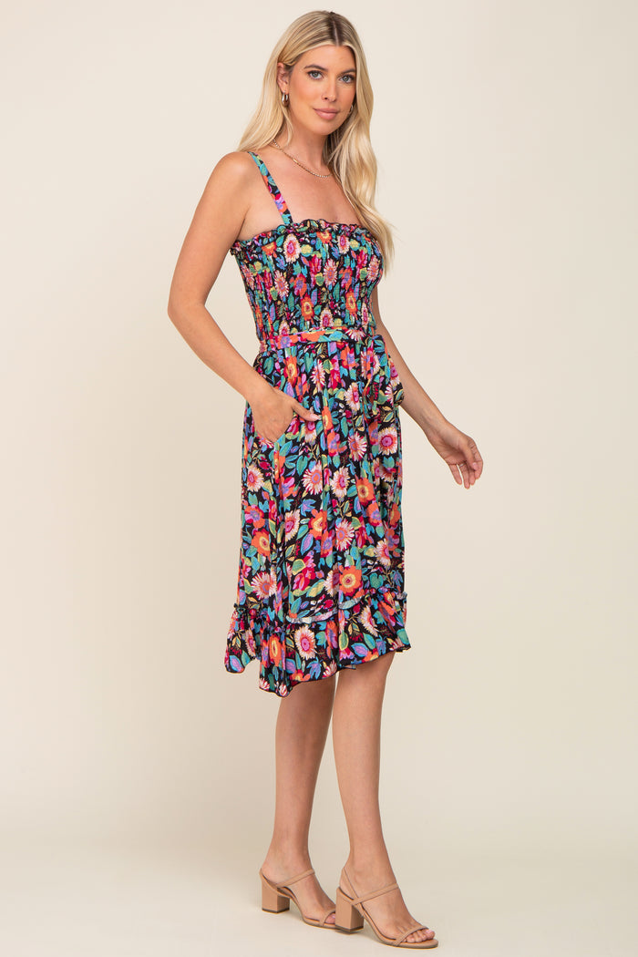 woman wearing a colorful floral print sundress with a smocked bodice and pockets, styled with beige heeled sandals