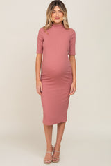 woman wearing a dusty rose ribbed maternity dress with a high neck and short sleeves, showing her baby bump