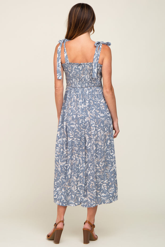 woman wearing a blue floral midi dress with tie straps and smocked back, view from the back