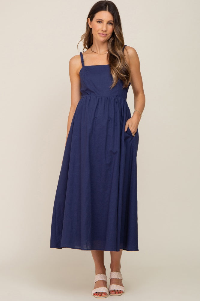 woman wearing a navy blue sleeveless maternity midi dress with pockets and square neckline