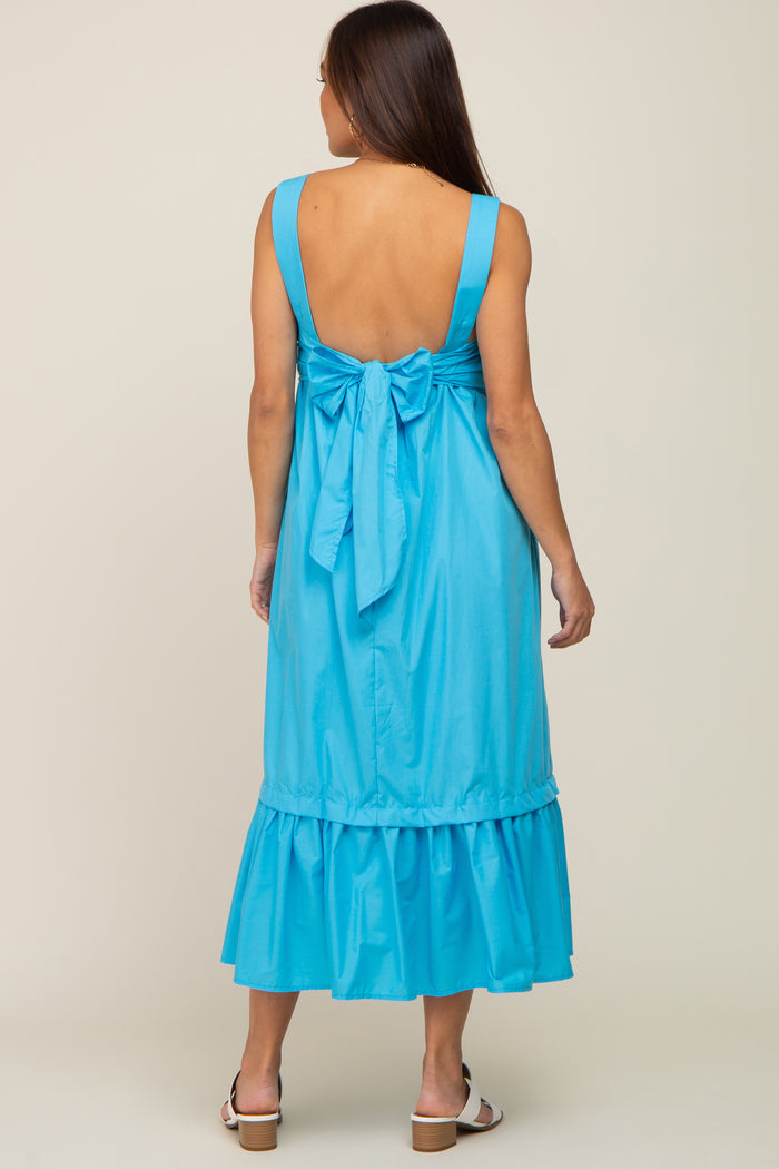 woman wearing a light blue maternity dress with a bow detail at the back and a ruffled hem
