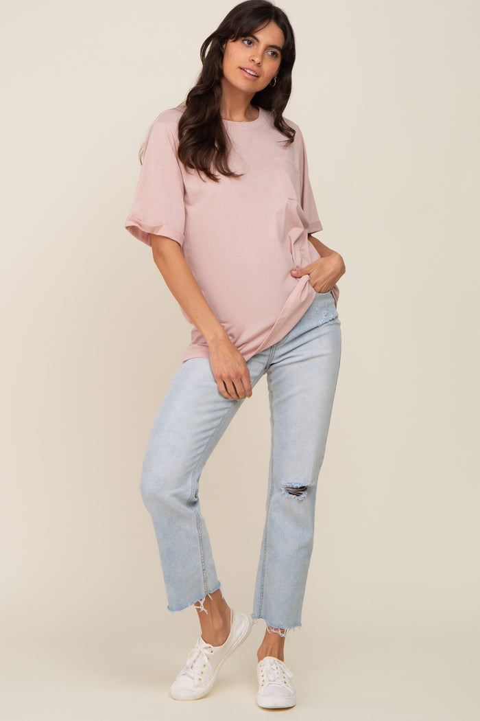 woman wearing a blush pink oversized t-shirt with rolled sleeves and light blue distressed jeans
