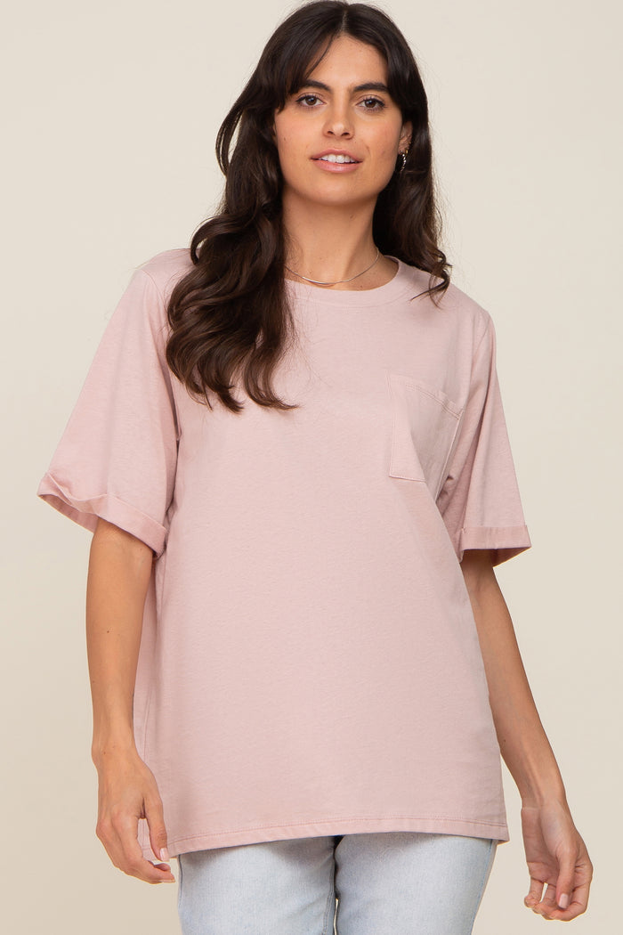 woman wearing a light pink oversized t-shirt with short sleeves and a front pocket.