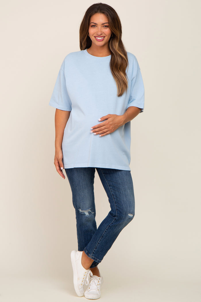smiling pregnant woman wearing light blue oversized maternity t-shirt and distressed jeans