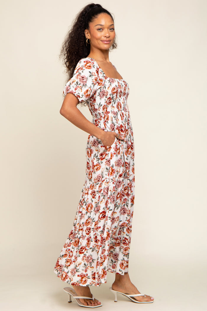 woman wearing a white floral maxi dress with puff sleeves and pockets, standing in a relaxed pose
