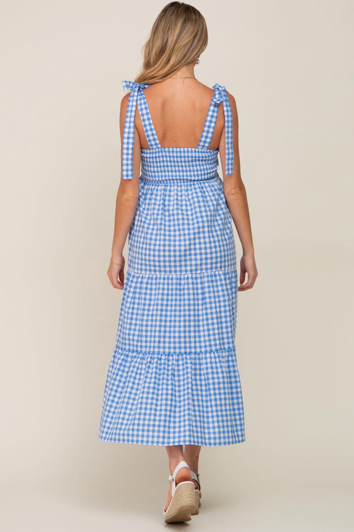 woman wearing a blue and white gingham maternity maxi dress with tie straps and a tiered skirt, showing her back