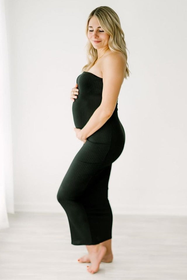 woman wearing a black strapless maternity dress and holding her baby bump