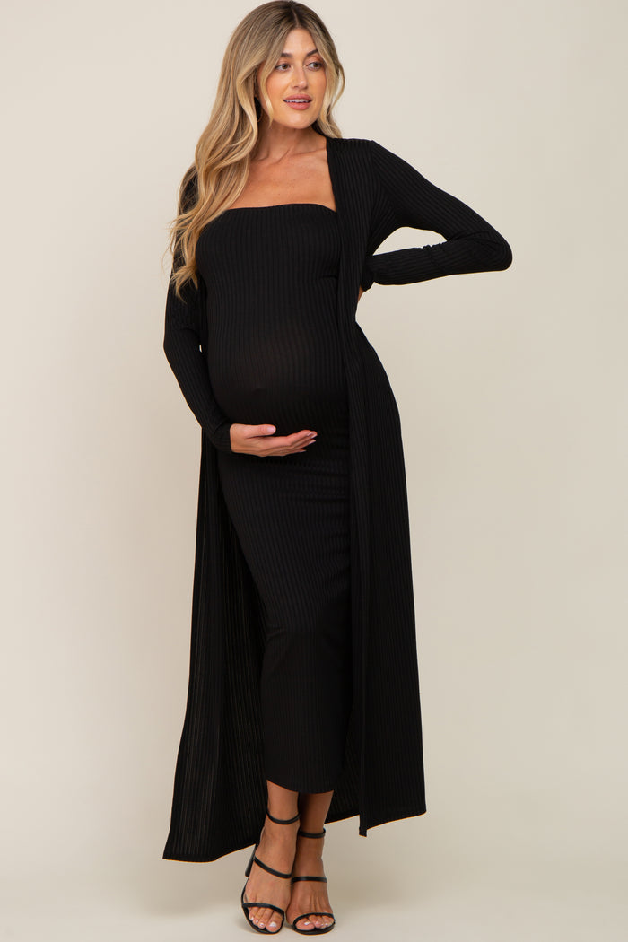 woman wearing a black ribbed maternity dress with a long cardigan, holding her baby bump